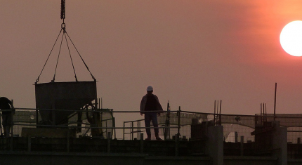 3 ouvriers sur un chantier au soleil couchant 